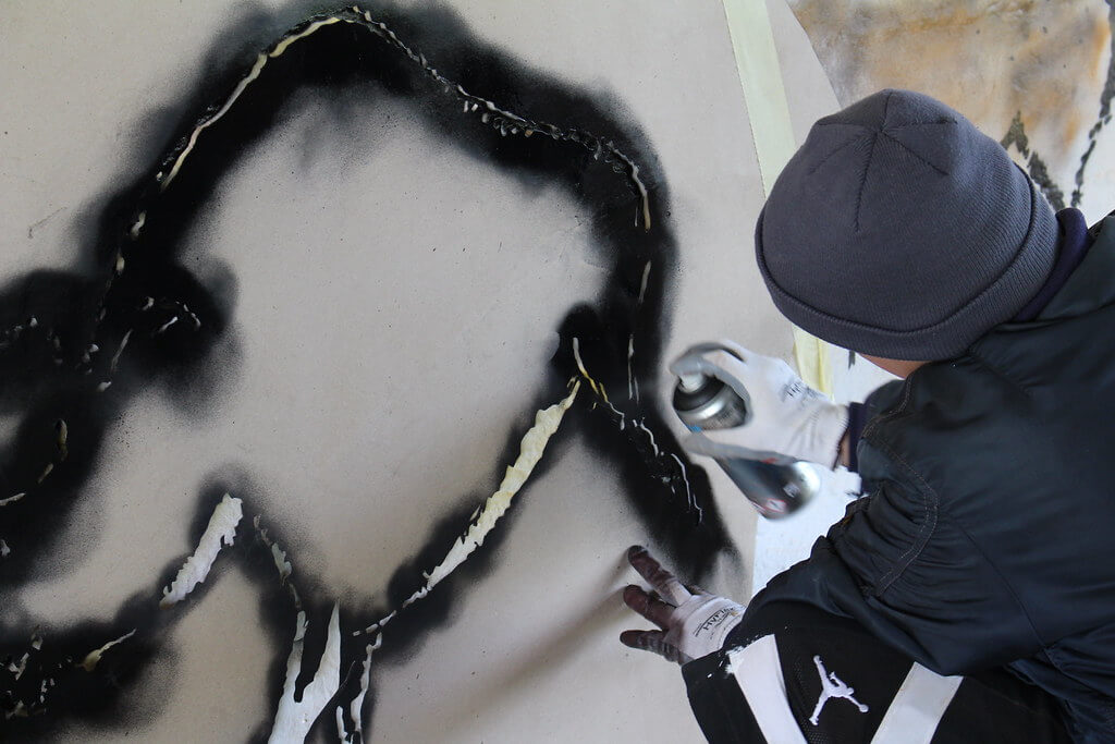 homme qui peint un tableaux street art au pochoir